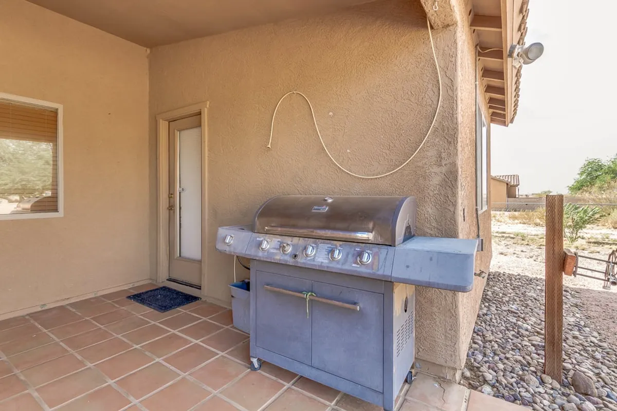 An inviting exterior shot highlighting a grill and the entry door, hinting at a welcoming patio area perfect for evening gatherings. The sky above is open, suggesting an ideal spot for enjoying twilight or night skies.