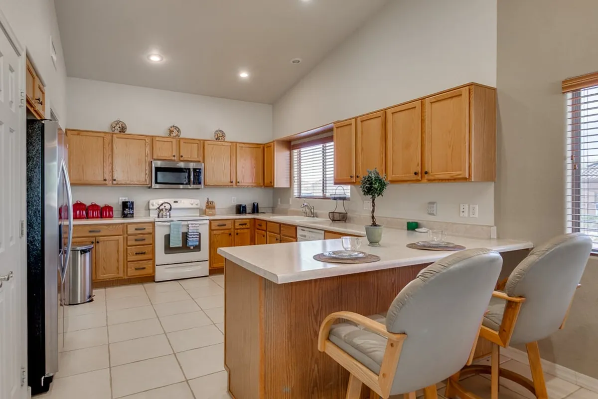A warm and welcoming kitchen scene featuring a spacious island, generous countertops, and modern appliances. The setup is clearly designed for both cooking and socializing, with ample workspace for multiple people to prepare meals together.
