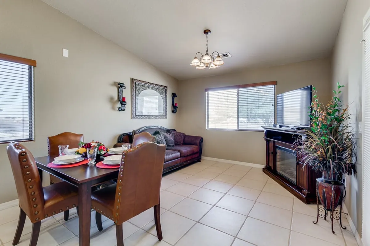 An open, welcoming lounge with a comfortable sofa facing a television, a stylish dining table set for a meal, decorative wall art, and a potted plant adding a touch of green. The layout encourages both relaxation and togetherness, making it ideal for family activities.