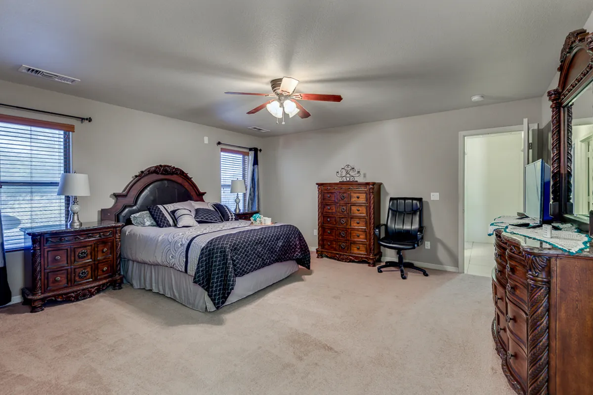 A serene bedroom featuring a queen-sized bed, a dresser, windows that allow natural light to stream in, and a cozy lamp. The atmosphere is peaceful and inviting, perfect for relaxation after a day of adventure.