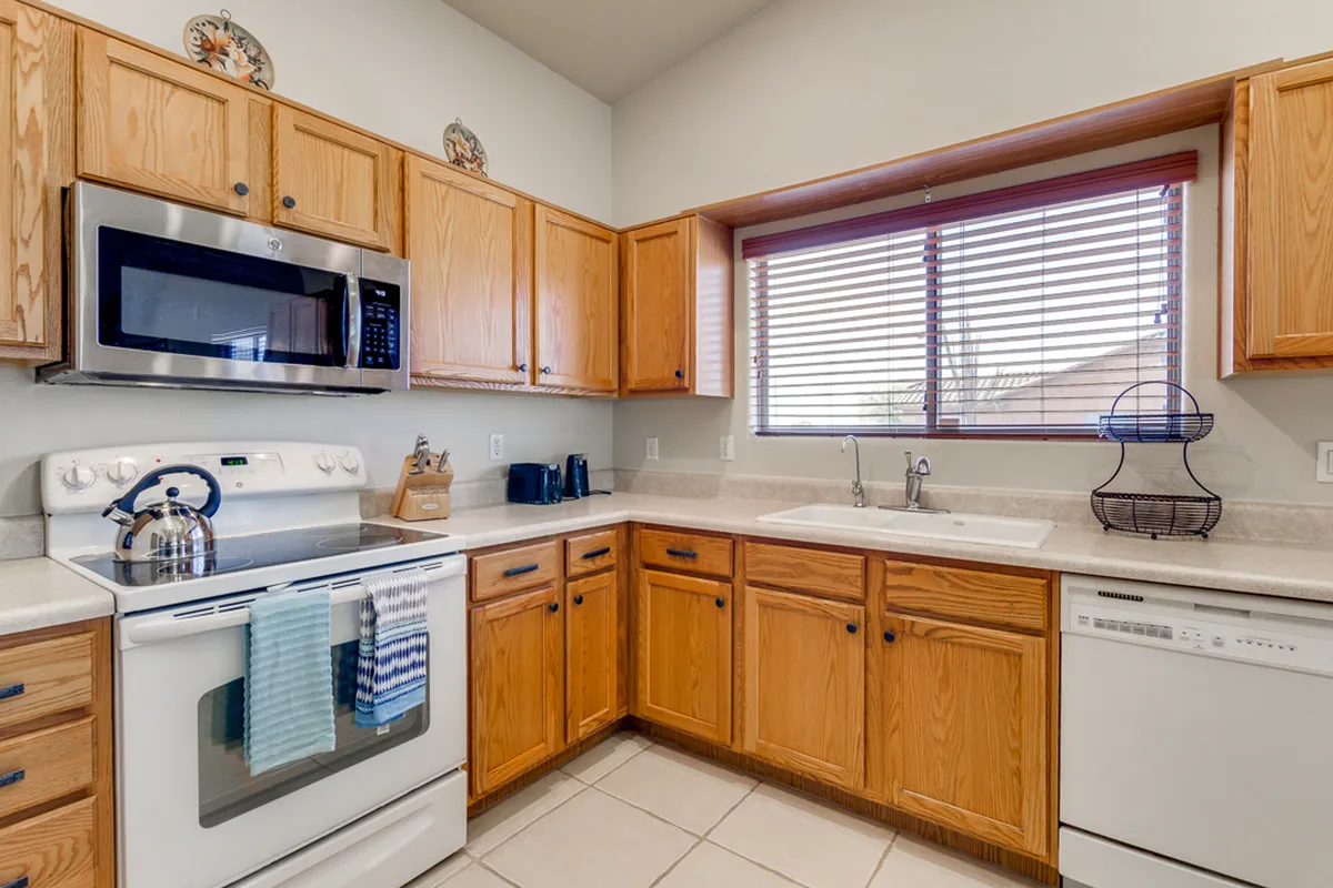 A kitchen scene with stainless steel appliances, wooden cabinets, a generously sized window, and a practical sink area. The setup radiates warmth and functionality, encouraging family traditions and holiday celebrations.