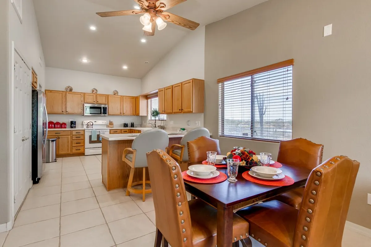 A cozy dining area adjacent to the kitchen, displaying a family-sized dining table, kitchen island, and a window letting in natural light. The arrangement highlights the flow between cooking and dining, perfect for shared meals and lively conversation.